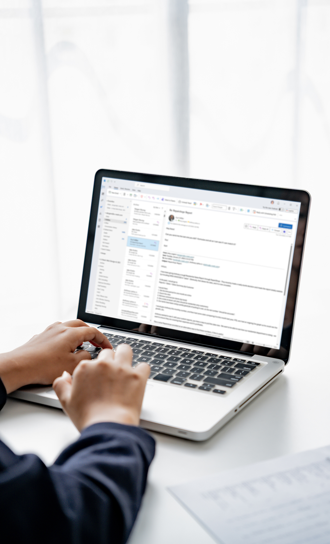 Office worker using Microsoft 365 business email on a laptop with Outlook inbox open in a modern office workspace, representing Office 365 support and business IT productivity tools